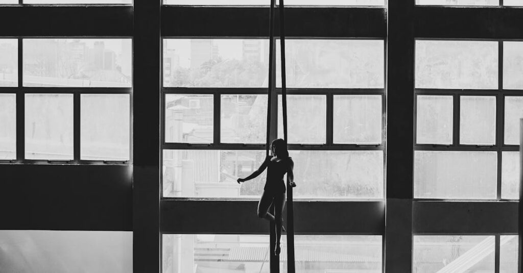 Aerial gymnast silhouetted against large windows in a Buenos Aires building.