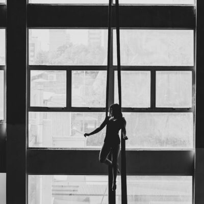 Aerial gymnast silhouetted against large windows in a Buenos Aires building.