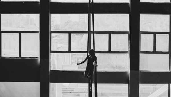Aerial gymnast silhouetted against large windows in a Buenos Aires building.
