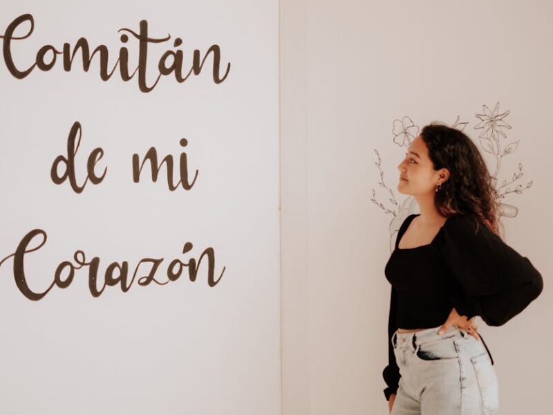 A woman in a black top and denim jeans admires a wall with 'Comitán de mi Corazón' text.
