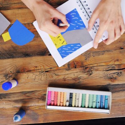 A vibrant arts and crafts setup with colorful papers and pastel colors on a wooden table.