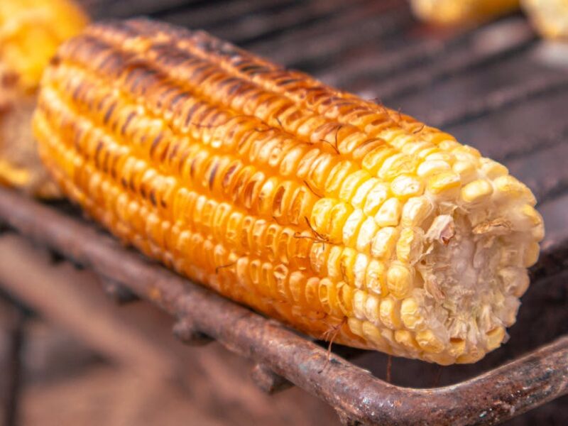 Close-up of grilled corn on the cob over a charcoal grill, capturing its golden texture and appetizing look.