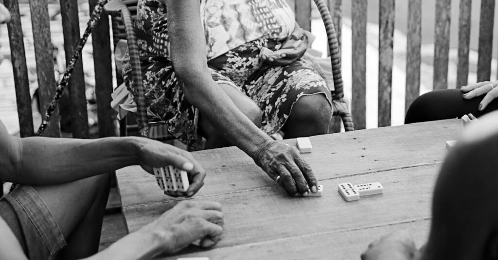 Black and white photo of people playing dominoes on a wooden table in Brazil.