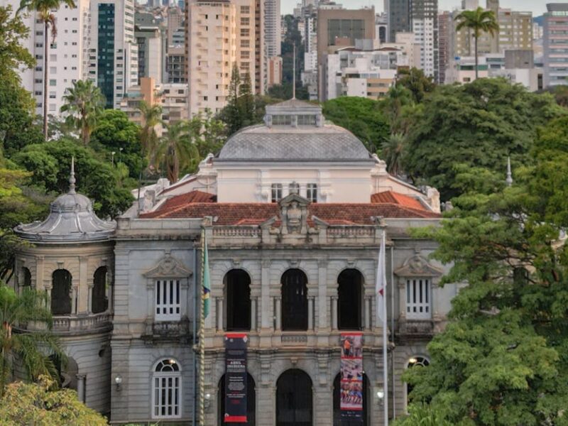 Elegant view of the Palace of Liberty surrounded by lush trees and modern skyline in Belo Horizonte, Brazil.
