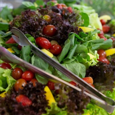 Vibrant mixed green salad with cherry tomatoes and fresh vegetables, perfect for a healthy meal.