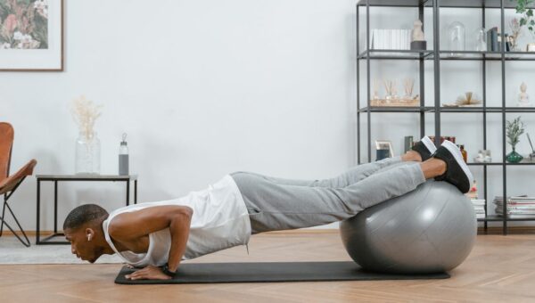 Adult doing push-ups with an exercise ball indoors for fitness and health.