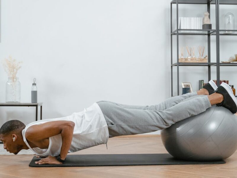 Adult doing push-ups with an exercise ball indoors for fitness and health.