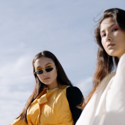 Fashionable women posing confidently in chic outfits under the clear sky.