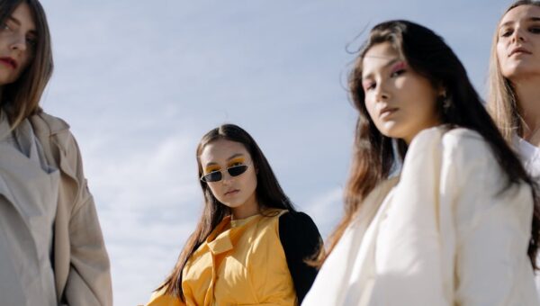 Fashionable women posing confidently in chic outfits under the clear sky.