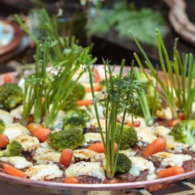 An artistic presentation of vegetables including broccoli, carrots, and greens on a copper platter.