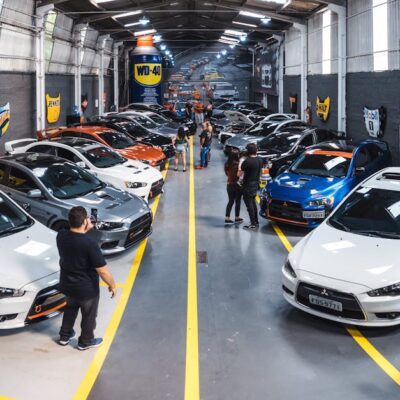 A vibrant scene of a car enthusiast gathering at Vila Nair, showcasing a variety of vehicles indoors.