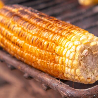 Close-up of grilled corn on the cob over a charcoal grill, capturing its golden texture and appetizing look.