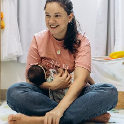 A joyful mother holding her baby in a bright, cozy room, showcasing motherhood and family warmth.