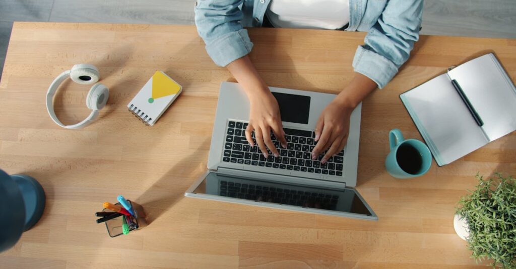 Top-down view of a person working on a laptop at a neat desk with accessories.