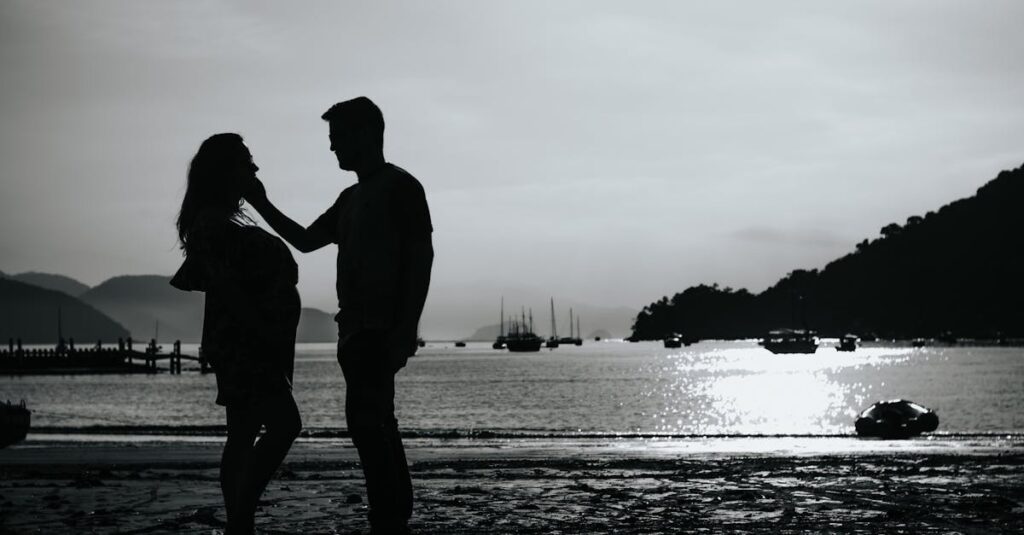 Black and white full body side view of anonymous couple caressing on shore near sea with various boats against pier