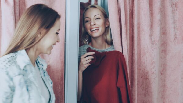 Two women enjoying a shopping experience, smiling in a changing room.