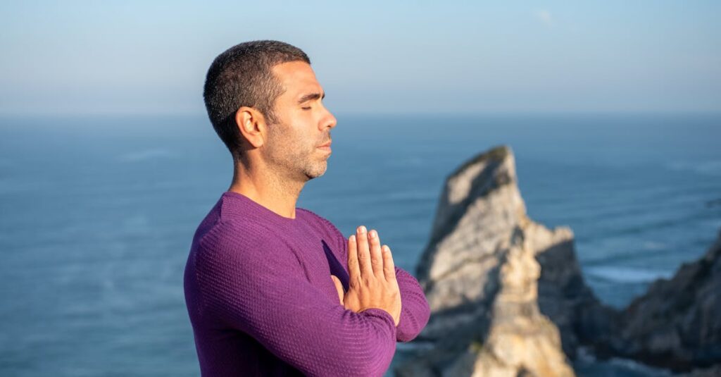 Side view of a man meditating by the ocean cliffs in Portugal, promoting relaxation and mindfulness.