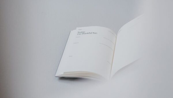 From above of opened notebook with empty pages placed on white working table