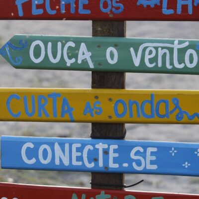 Vibrant wooden sign with motivational phrases on a beach in Guaratuba, Brazil.