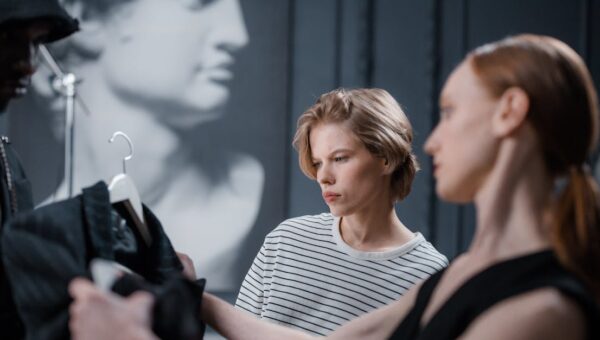 Fashion designers collaborate while reviewing a garment in a modern studio setting.