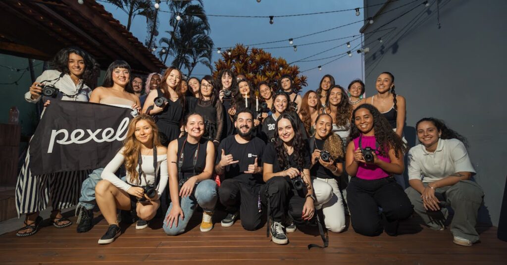A diverse group of photographers pose outdoors at a photography meetup, showcasing their cameras.