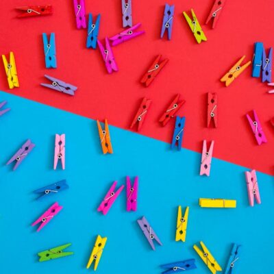 Colorful clothespins scattered on a contrasting red and blue background for a vibrant look.