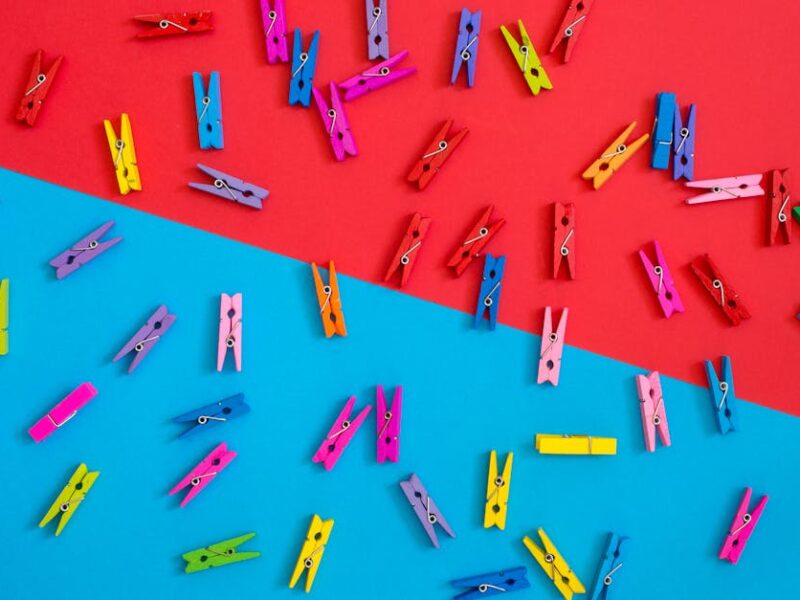 Colorful clothespins scattered on a contrasting red and blue background for a vibrant look.