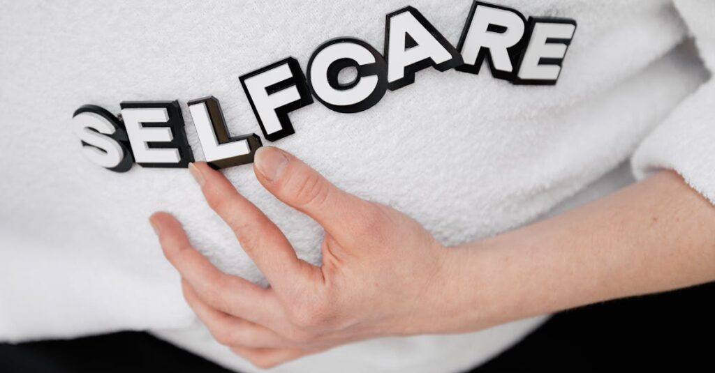Close-up of a hand holding the word 'self-care' made with 3D letters on a white background.
