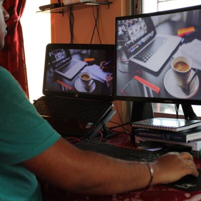 A person working from home in Kolkata with dual monitors, coffee, and headphones. Ideal for remote work concepts.