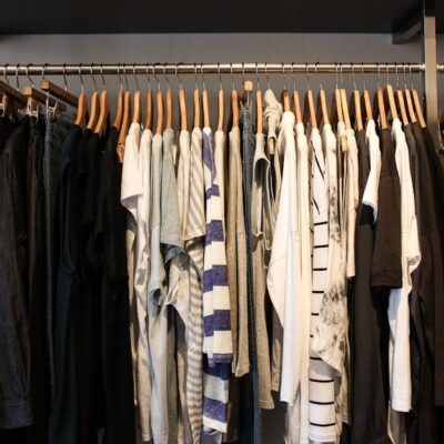 Diverse range of fashionable clothes on wooden hangers in a boutique setting.