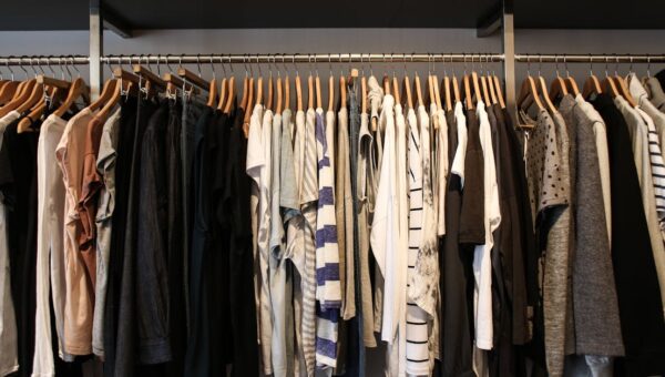 Diverse range of fashionable clothes on wooden hangers in a boutique setting.