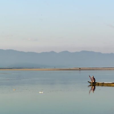 A serene view of a fisherman in a boat on the calm Brahmaputra River near Biswanath Charali, Assam.