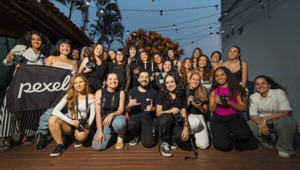 A diverse group of photographers pose outdoors at a photography meetup, showcasing their cameras.