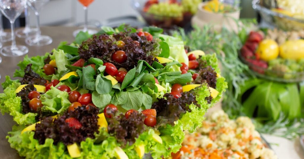 Colorful mixed salad with leafy greens, cherry tomatoes, and mango slices on a buffet table.