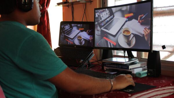 A person working from home in Kolkata with dual monitors, coffee, and headphones. Ideal for remote work concepts.