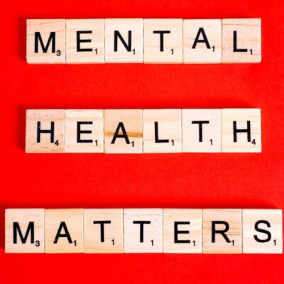 Wooden tiles spelling 'Mental Health Matters' on a vivid red background.