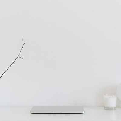 A clean, minimalistic workspace featuring a white desk, laptop, and decorative items, perfect for modern design inspiration.