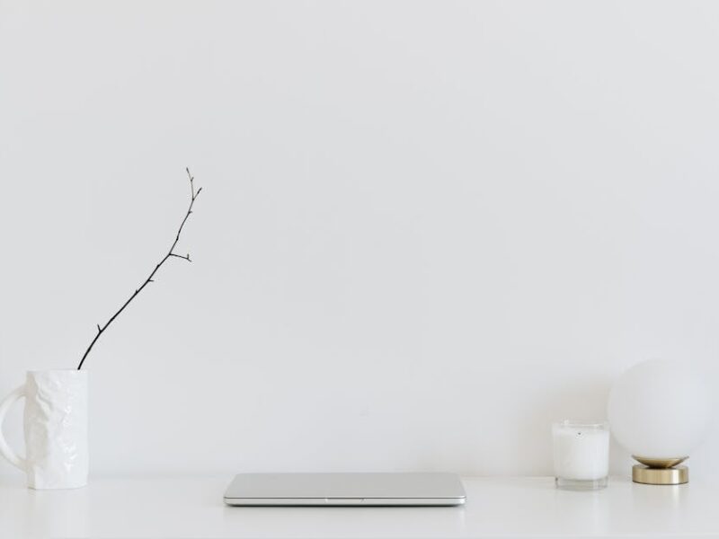 A clean, minimalistic workspace featuring a white desk, laptop, and decorative items, perfect for modern design inspiration.