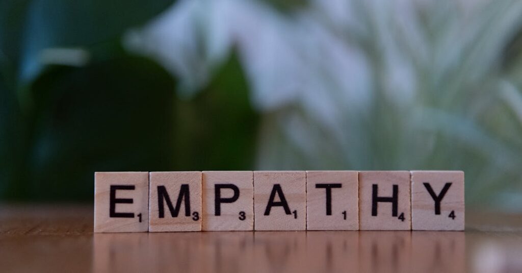 Close-up of tiles spelling empathy on a wooden surface with blurred green background.