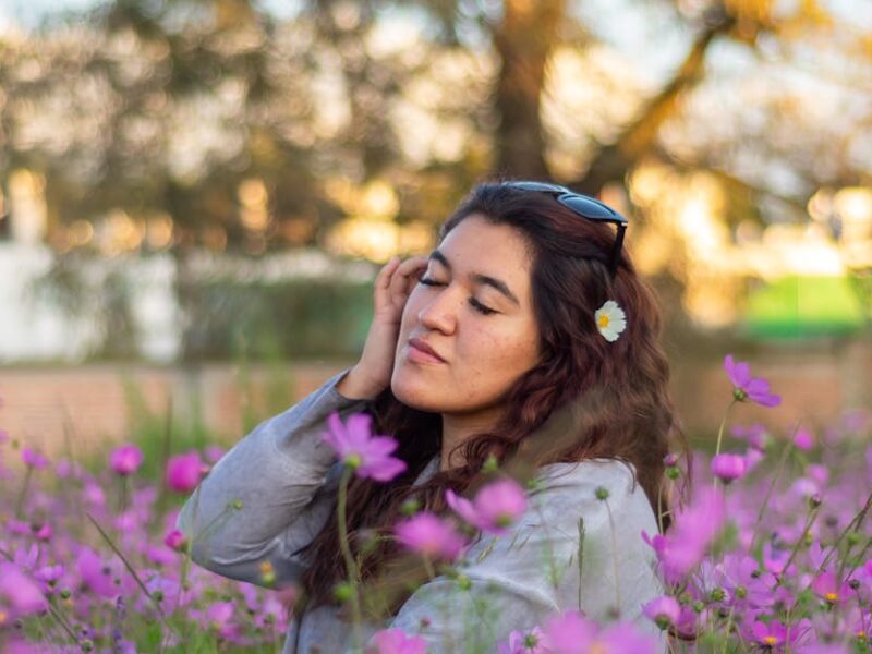 Young woman enjoying a moment in a field of vibrant purple cosmos flowers.