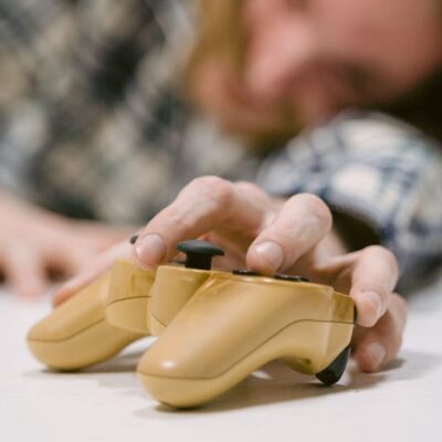 Hand reaching out to touch a yellow game controller, focus on interaction.