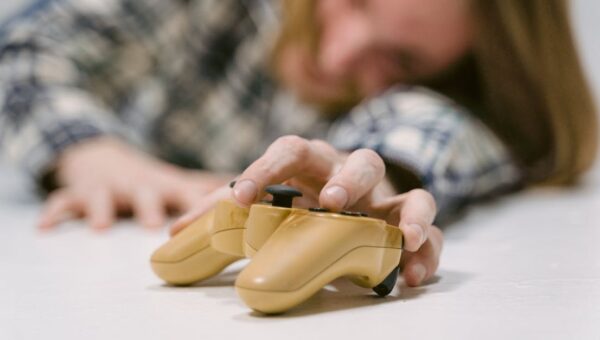 Hand reaching out to touch a yellow game controller, focus on interaction.
