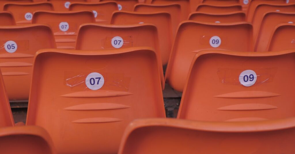 Rows of empty orange plastic stadium seats with visible numbered labels