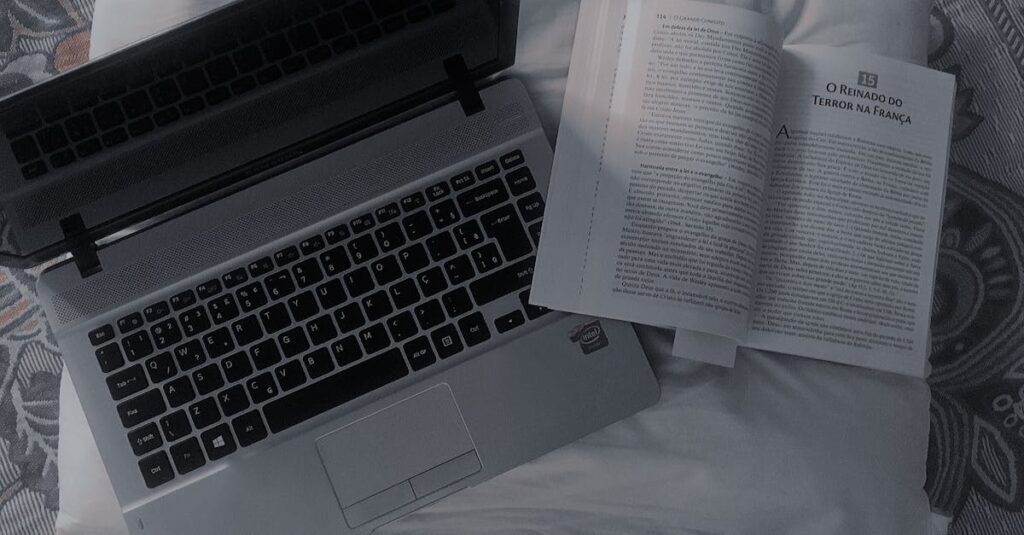 A comfortable setup featuring an open book and laptop on a bed, offering a cozy reading and work space.