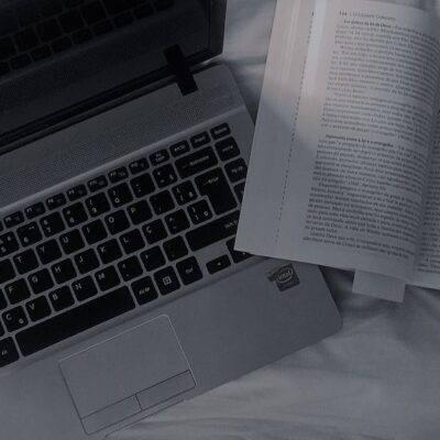 A comfortable setup featuring an open book and laptop on a bed, offering a cozy reading and work space.