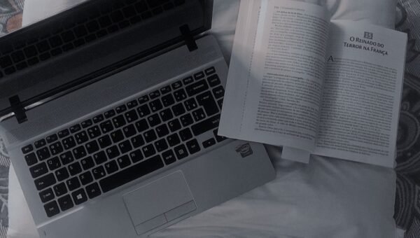 A comfortable setup featuring an open book and laptop on a bed, offering a cozy reading and work space.