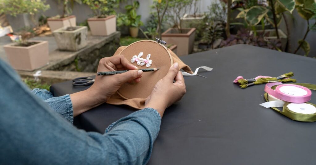 Hands embroidering outdoors with ribbons and yarns, showcasing arts and crafts.