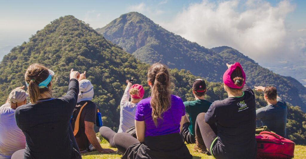 A diverse group of hikers enjoying a scenic mountain view while sitting on grass during the day.