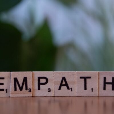 Close-up of tiles spelling empathy on a wooden surface with blurred green background.