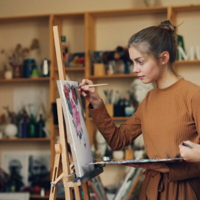 Two women engaged in creating art on canvas, showcasing creativity and concentration.